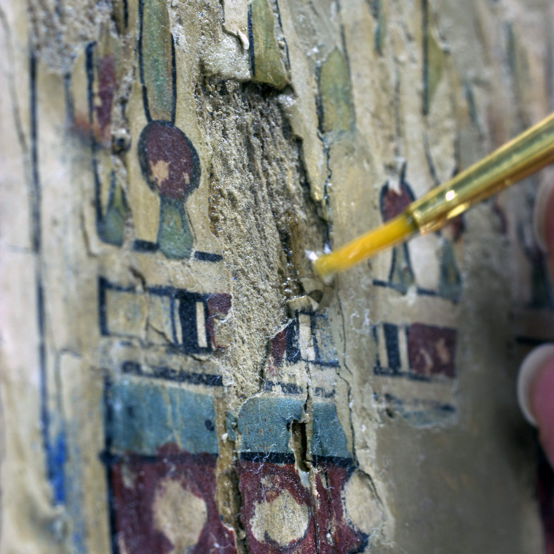 Conservator uses a paintbrush to treat a piece of art
