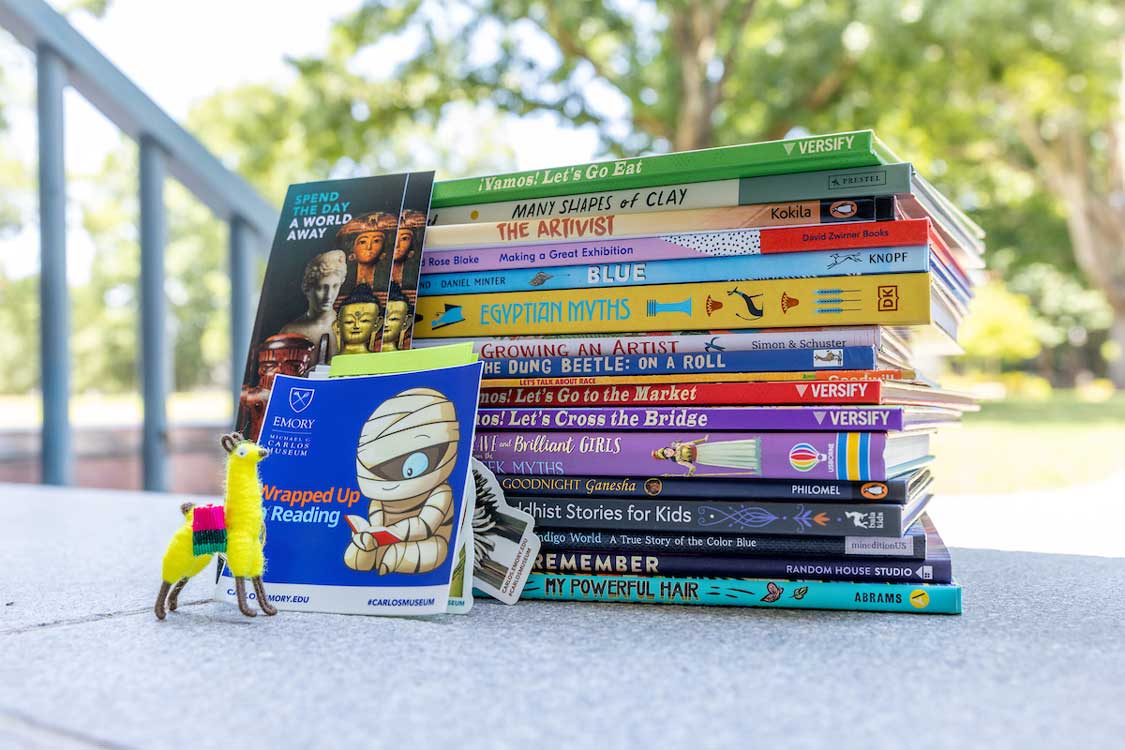 Image of a stack of books from the Wrapped up in Reading List sitting on the museum's steps